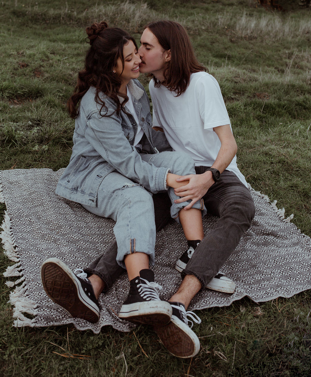 Couple kissing & holding hands on a picnic blanket in the Victorian countryside.